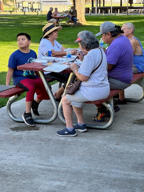 Children and adults eat tacos at community park