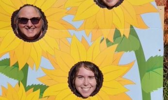 People pose with a sunflower photo cutout