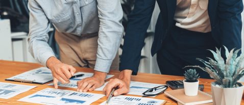 Analyst team in office analyzing financial data analysis for marketing strategy in workspace, pile of BI dashboard paper format with graph and chart to optimize performance and risk management. Entity
