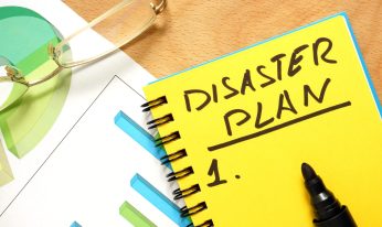 Notepad with disaster plan on a wooden table.