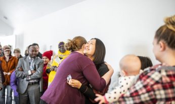 An image of a woman happily embracing another at a Habitate for Humanity function.