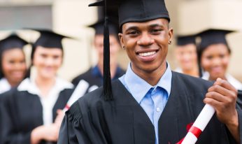 good looking african american male graduate in front of classmates