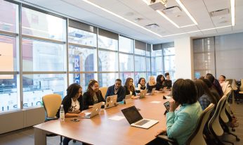 Board members meet around a wooden table.