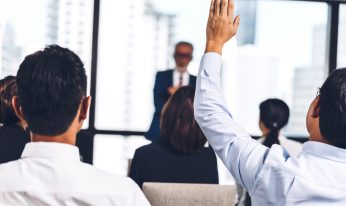 Businessman standing in front of group of people in consulting meeting conference seminar and showing hand to answer question at hall or seminar room.presentation and coaching concept